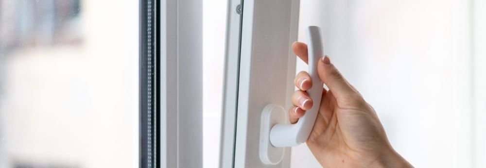 Hand öffnet Fenstergriff